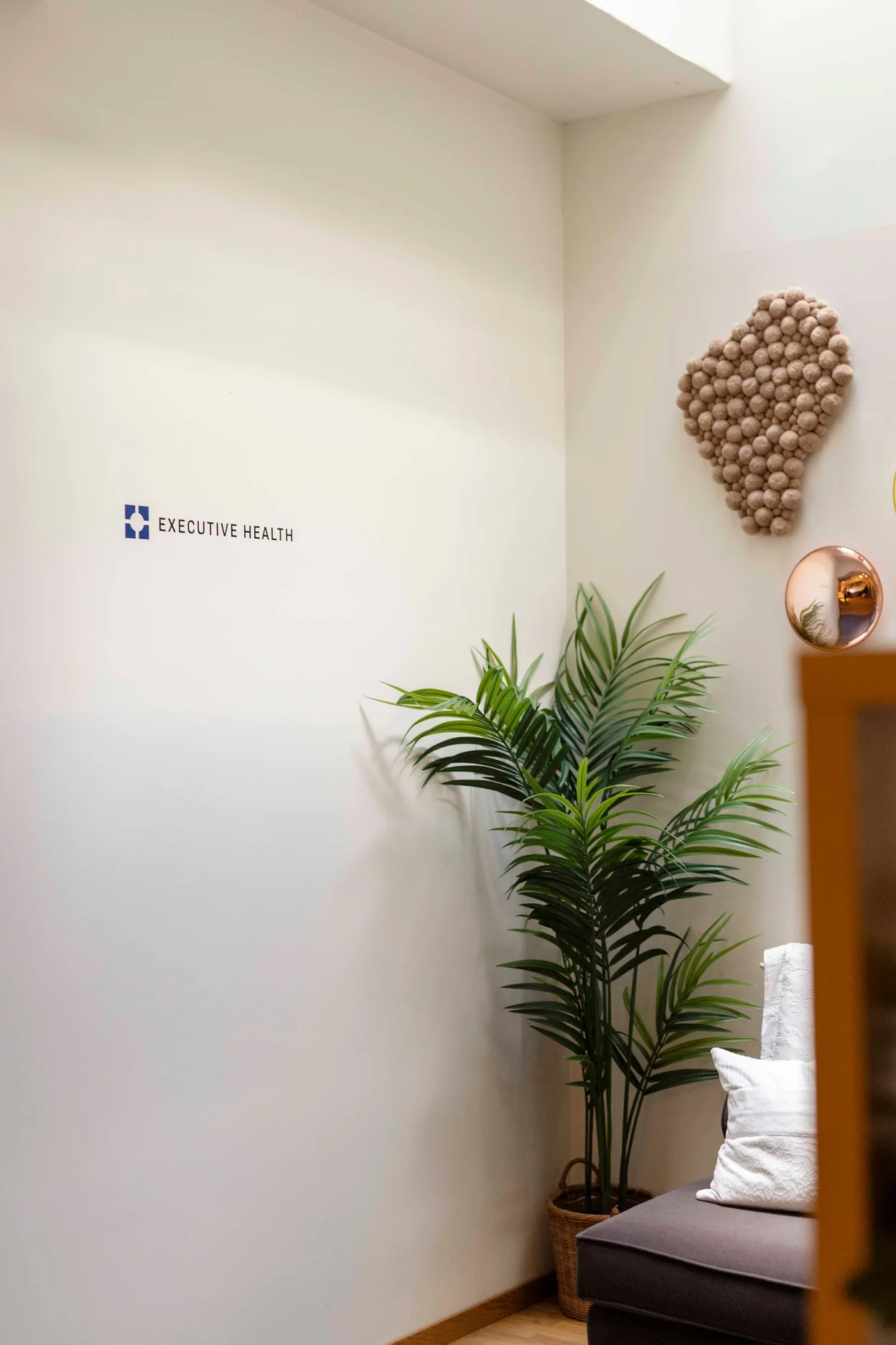 Executive Health clinic waiting area with logo signage, plants, and seating.